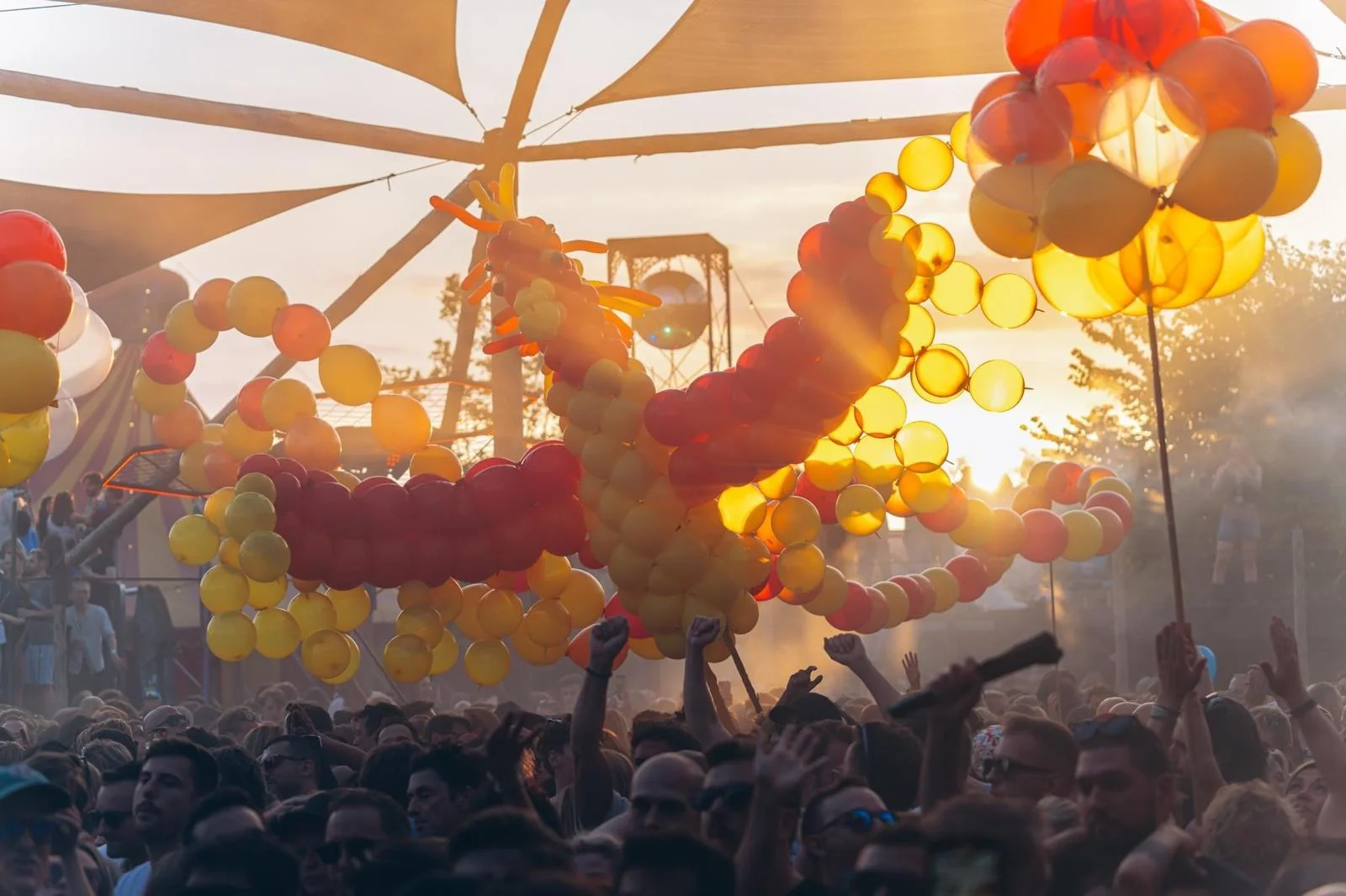 Phoenix balloon sculpture soaring above the crowd at sunset