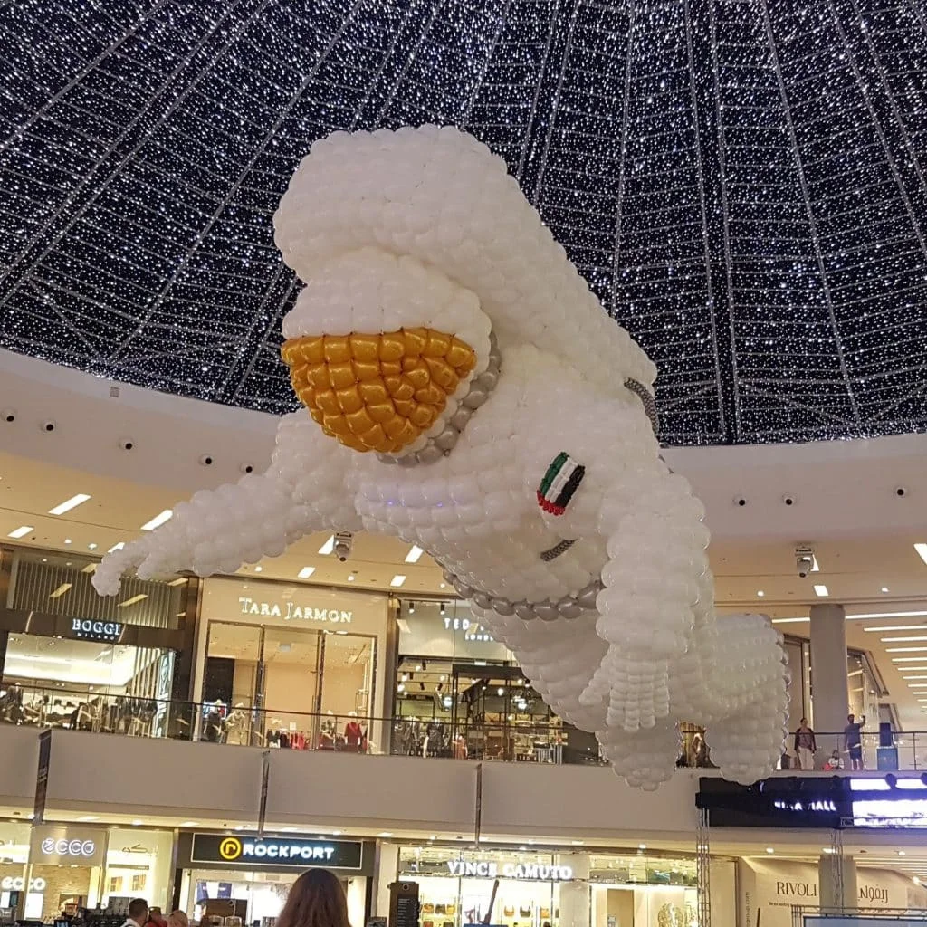 Stages of Air — Giant white balloon astronaut sculpture with golden visor in Dubai shopping mall